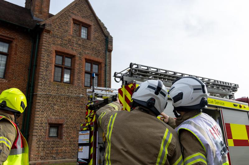 Firefighter crews observe Chartwell House from outside their fire engines.