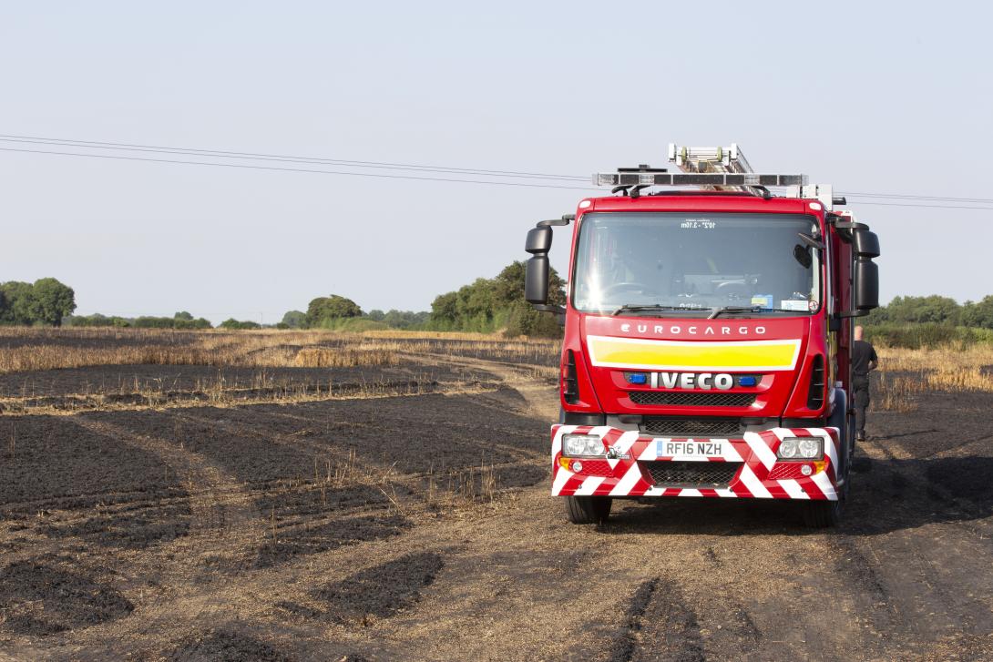 A fire engine in a burnt field.