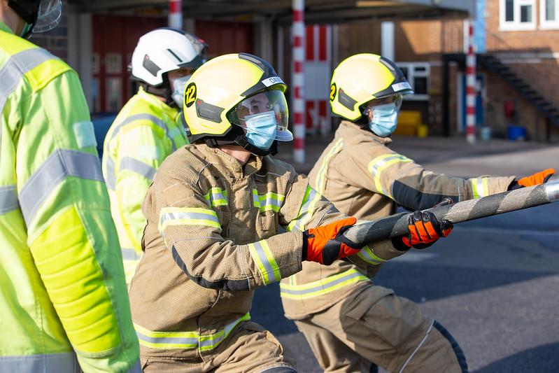 Three fire men pulling a pole