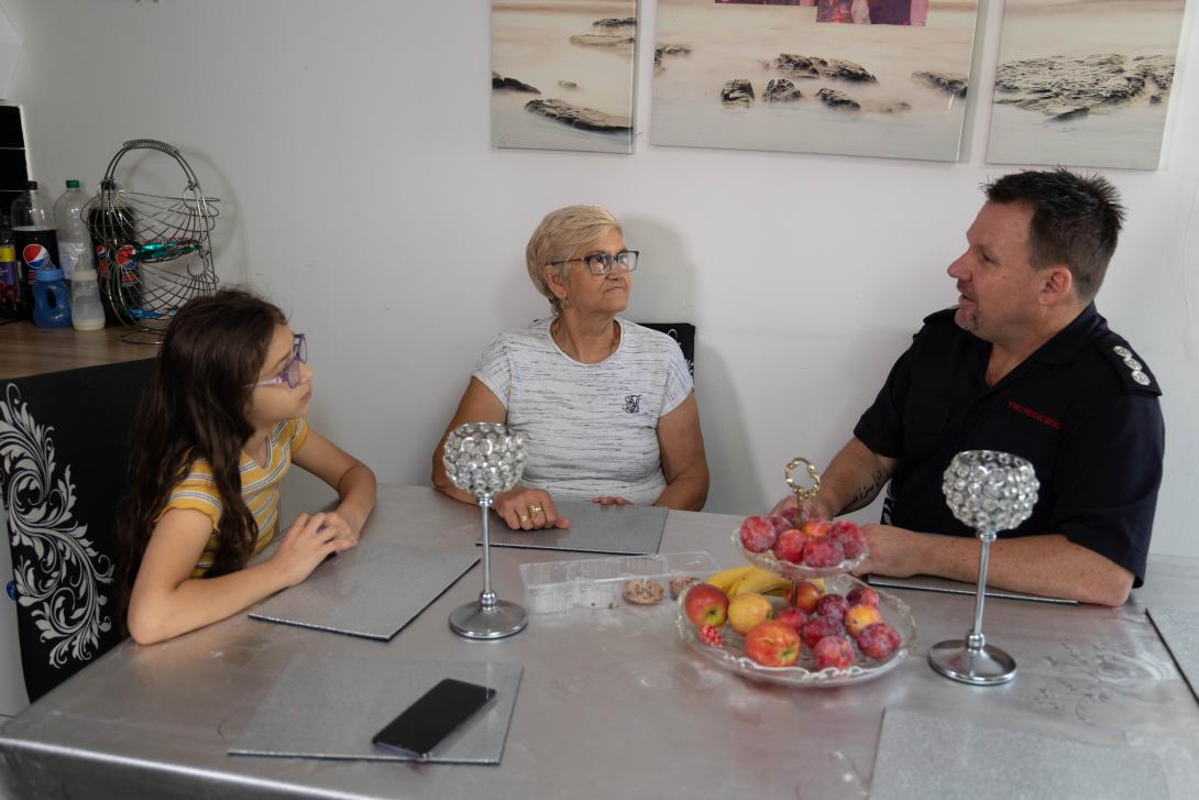 Female child and woman talking to a firefighter at a dining table