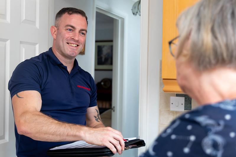 A safe and well male colleague talking to a lady in her home