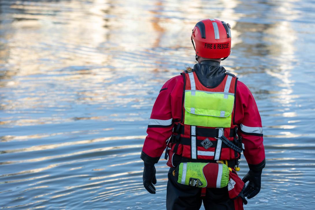 Person wearing water rescue PPE looking over a lake