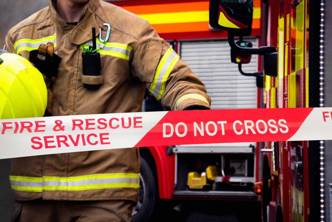 fire fighter in front of 'do not cross' barrier