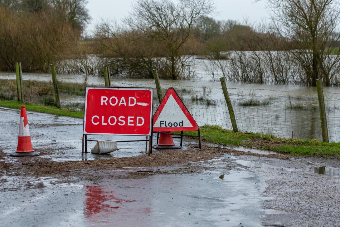 flooded country road with 'road closed' and 'flood' signs 