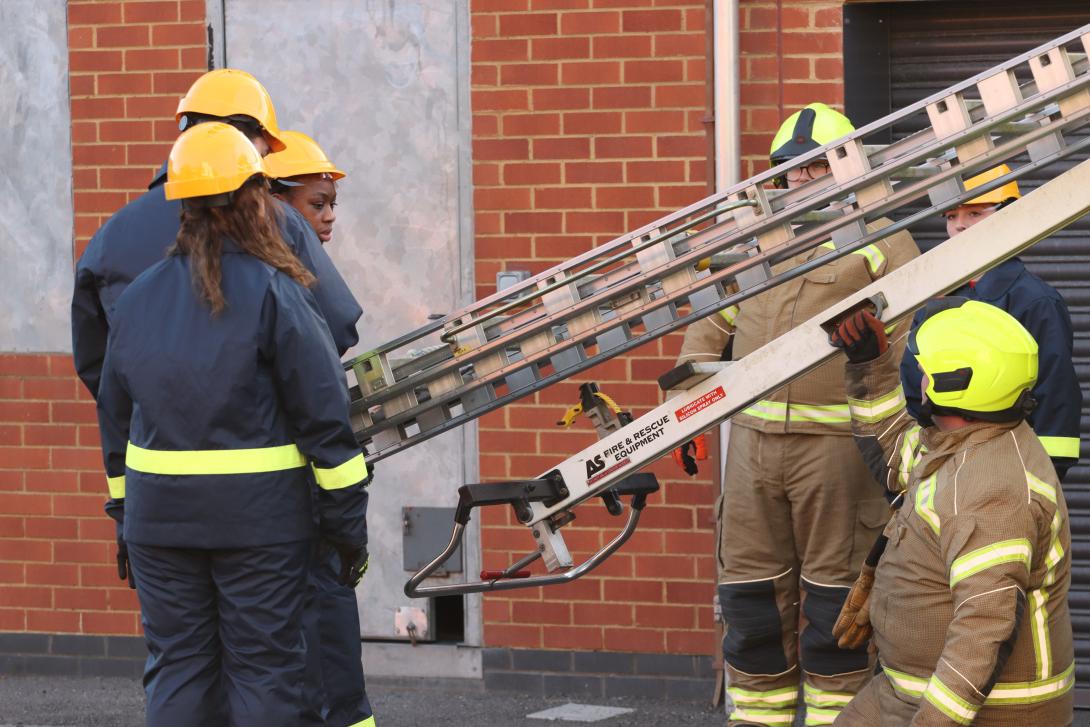 fire cadets carrying a ladder with support from volunteers