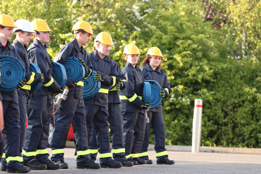 Fire cadets lined up, holding on to rolled up hoses