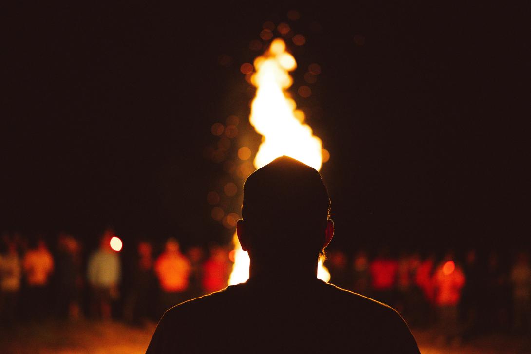 Image of a young person standing in front of a bonfire